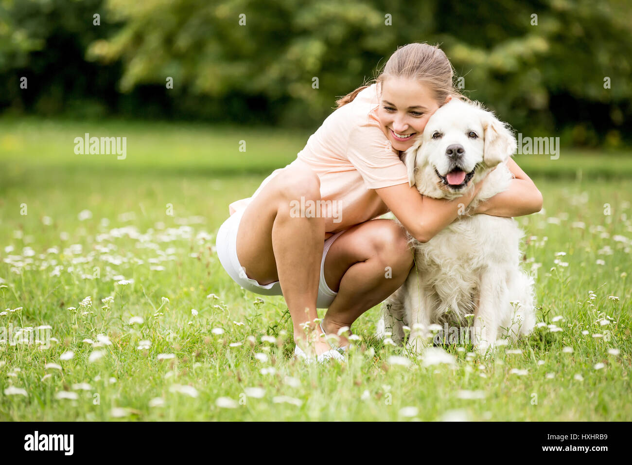 Frau umarmt Hund mit Liebe auf den Garten im Sommer als Freundschaft Konzept Stockfoto