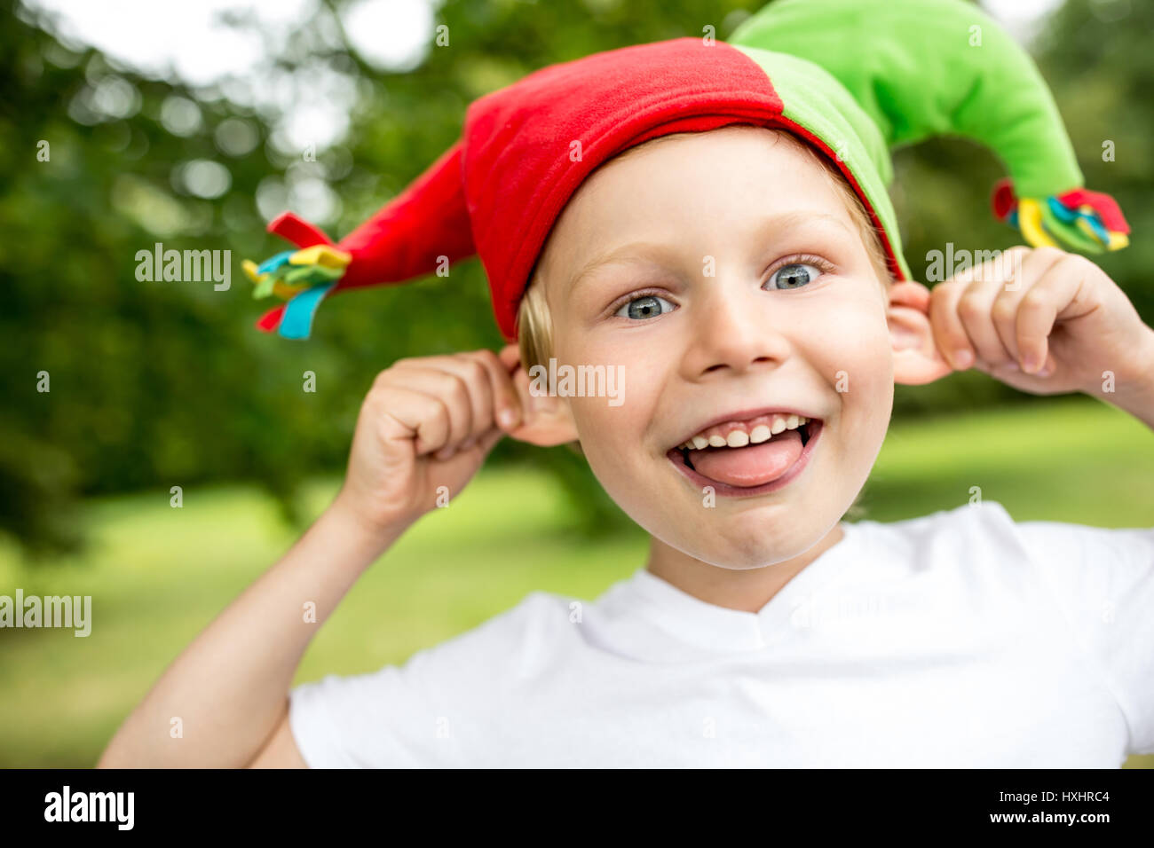 Junge mit Mütze Narr zieht seine Ohren und Spaß Stockfoto