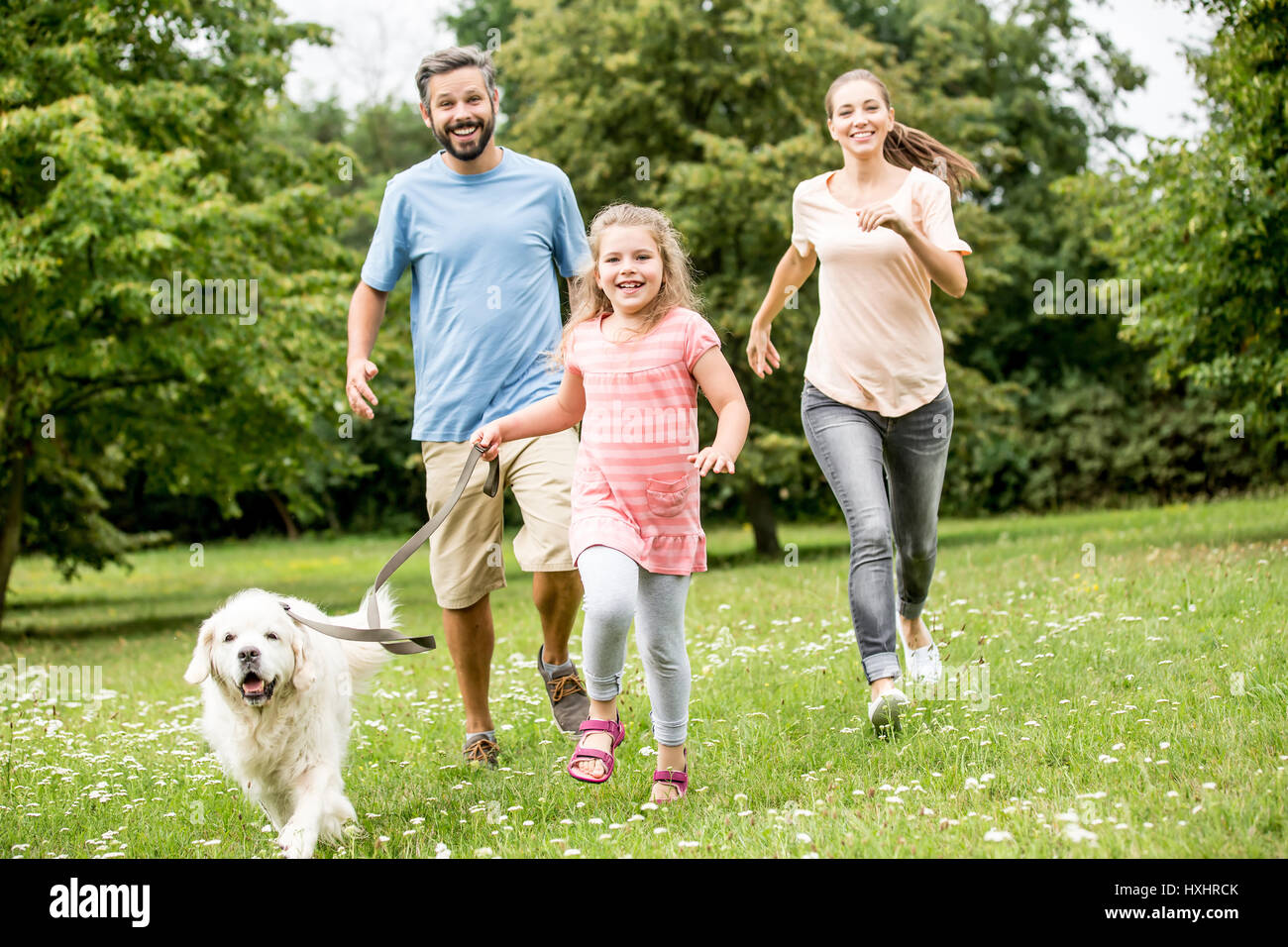 Mädchen und Eltern mit Golden Retriever als Familie im park Stockfoto