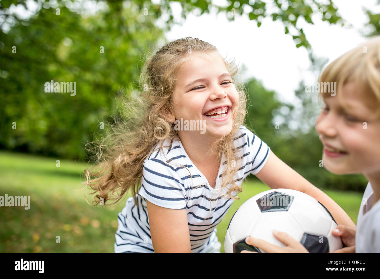 Gril spielt Fußball mit Bruder Lachen und Spaß Stockfoto