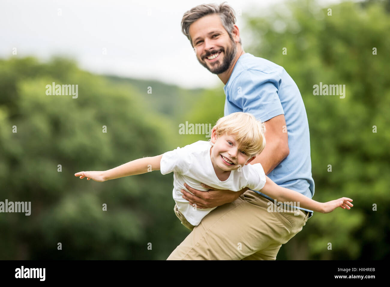 Vater mit Sohn spielt und trägt ihn wie ein Flugzeug Stockfoto