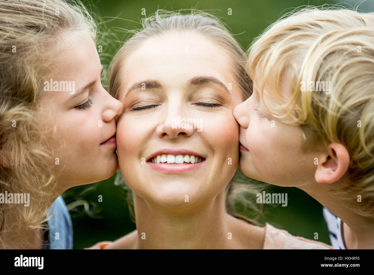 Kinder küssen Mutter mit Liebe als eine glückliche Familie Stockfoto