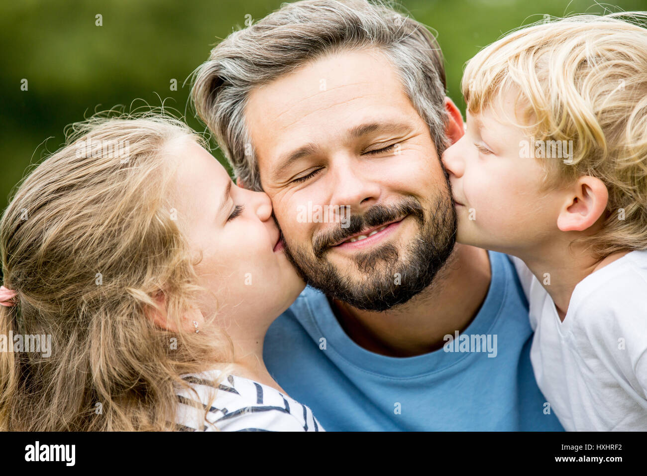 Glückliche Kinder geben Vater einen Kuss mit Liebe Stockfoto