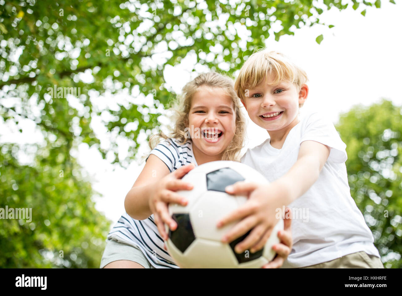 Kinder als Bruder und Schwester mit Fußball im Sommer Stockfoto