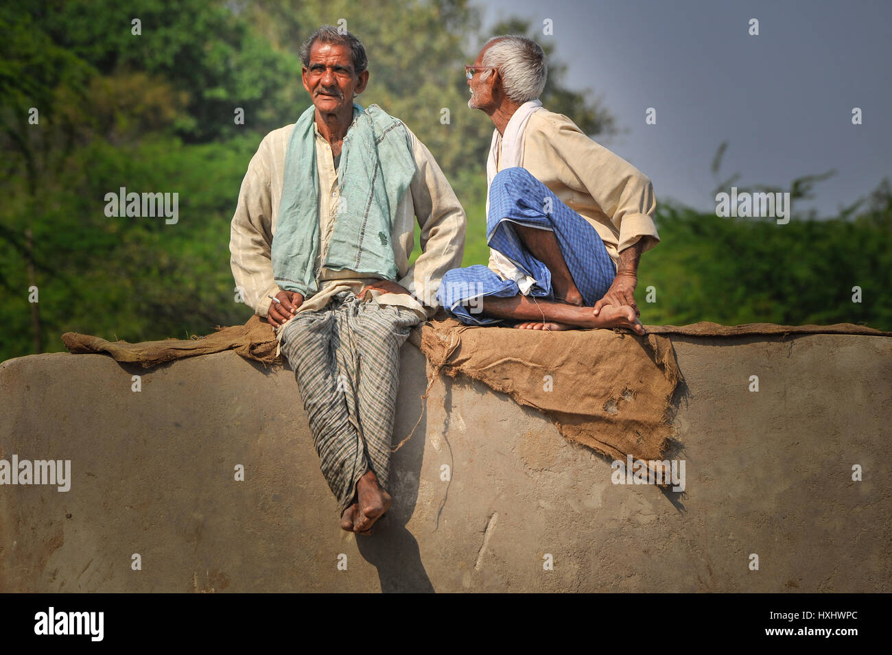 Zwei indische Männer sitzen und reden auf einem Betonblock Stockfoto
