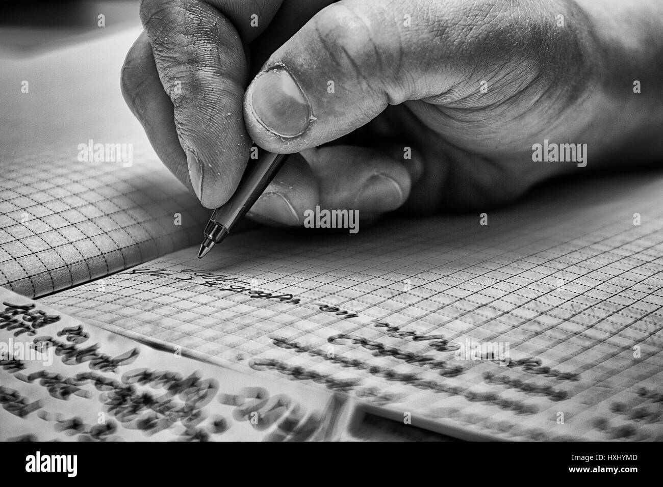 Eine männliche Hand ist in einem großen Notizbuch auf einem Holztisch schreiben. Stockfoto