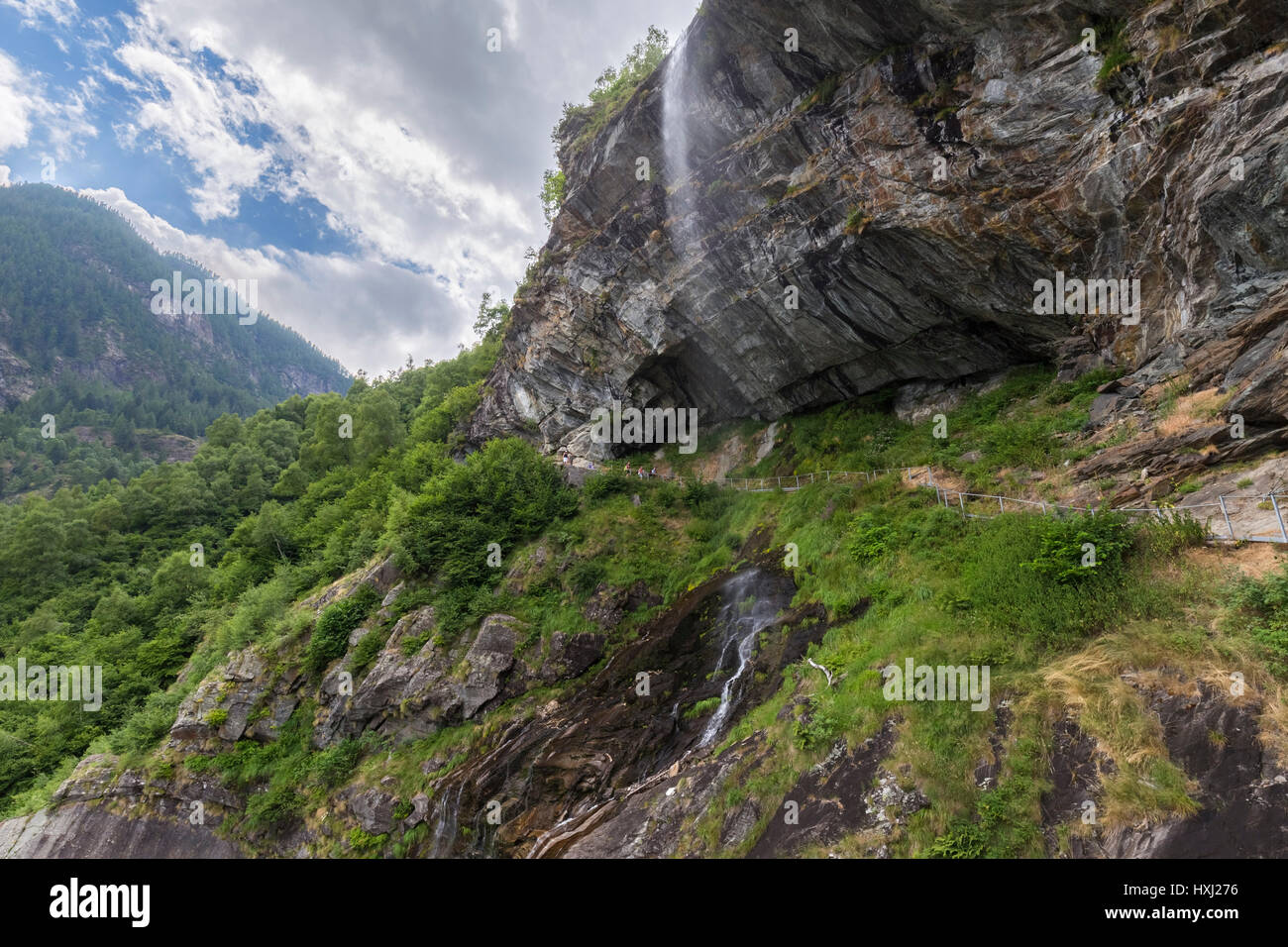 Laufsteg unter einem Wasserfall auf dem Weg rund um den Lago di Antrona, Valle Antrona, Piemont, Italien. Stockfoto