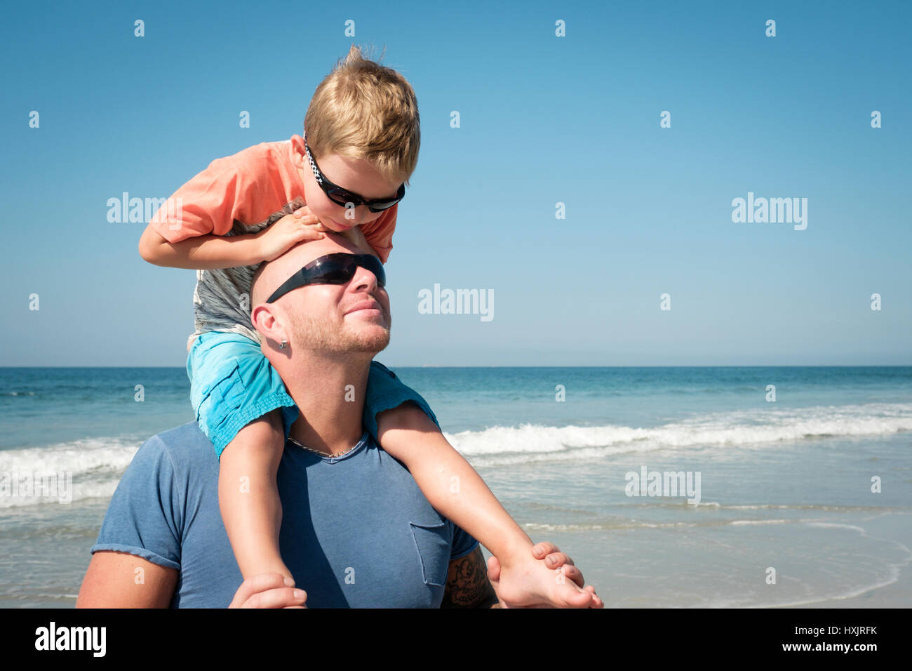 Vater mit seinem kleinen Sohn auf Schultern genießen Familientag am Strand Stockfoto