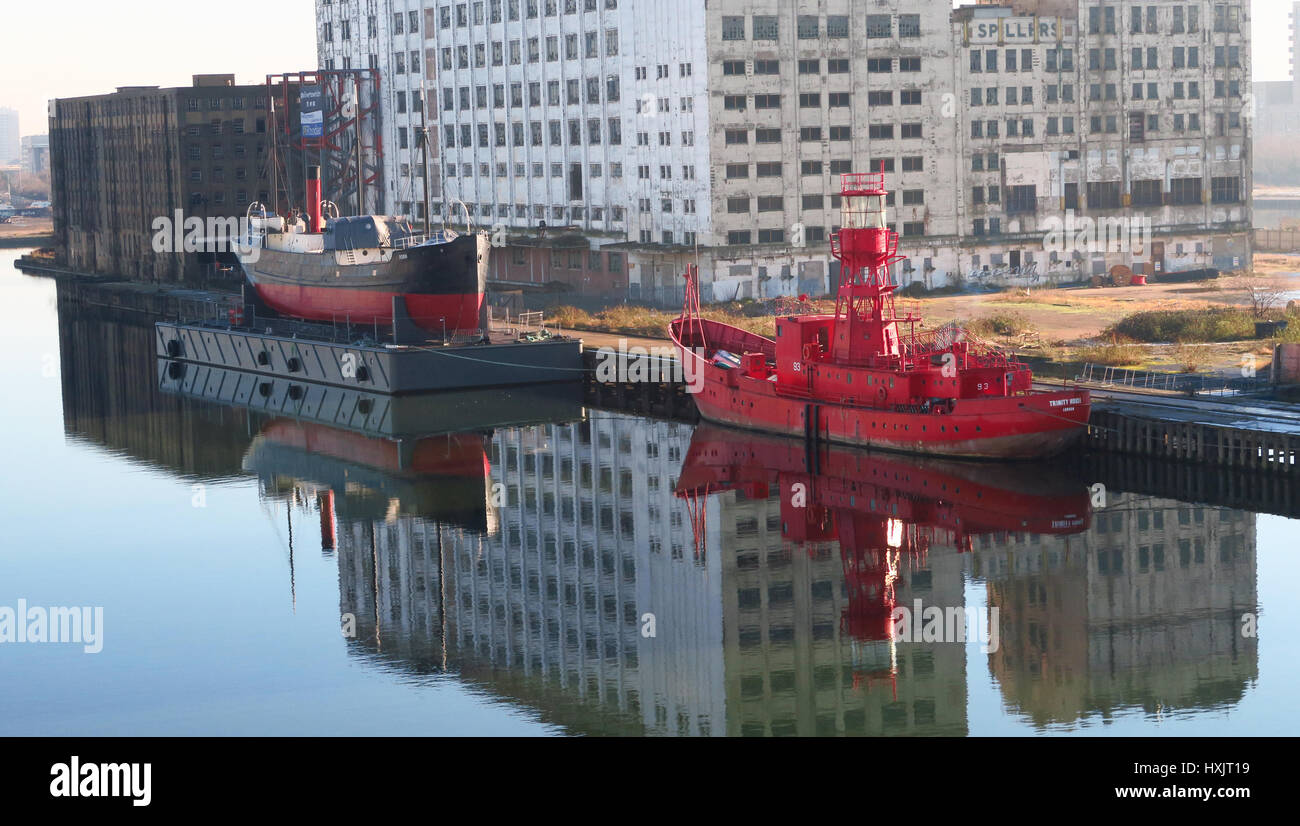 Form versenden. Zwei alte Schiffe nun dauerhaft in der Royal Victoria Dock, London günstig. Lebendige Reflexionen der Schiffe und ein verfallenes Gebäude. Stockfoto