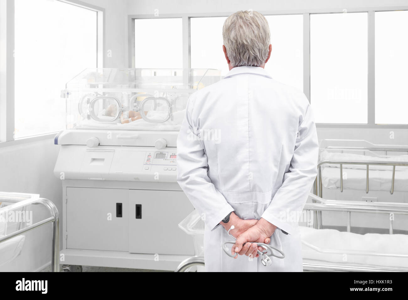 Leitender Arzt mit Stethoskop neugeborenes Baby betrachten bedeckt in Brutmaschine in Post-Kreißsaal Stockfoto