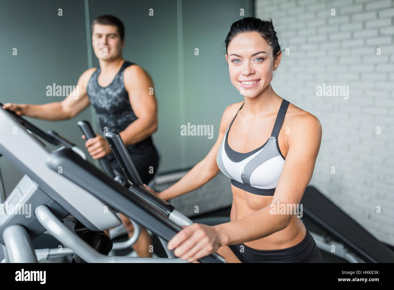 Lächelnde Menschen Fitness Working Out auf Maschinen im Fitness-Studio Stockfoto