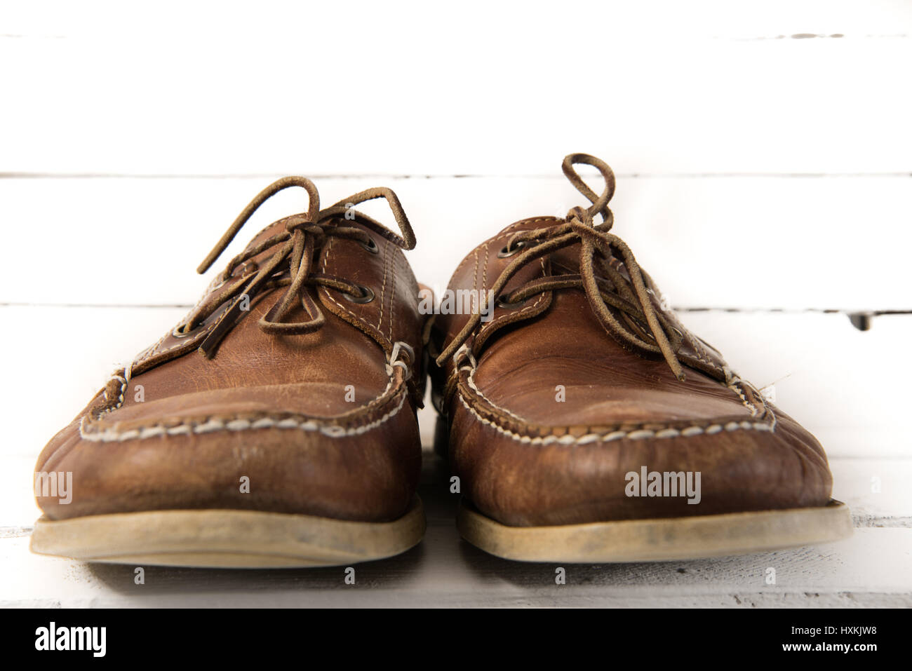 Paar von abgenutzten casual Leder Schuhe vor weißem Hintergrund aus Holz Stockfoto