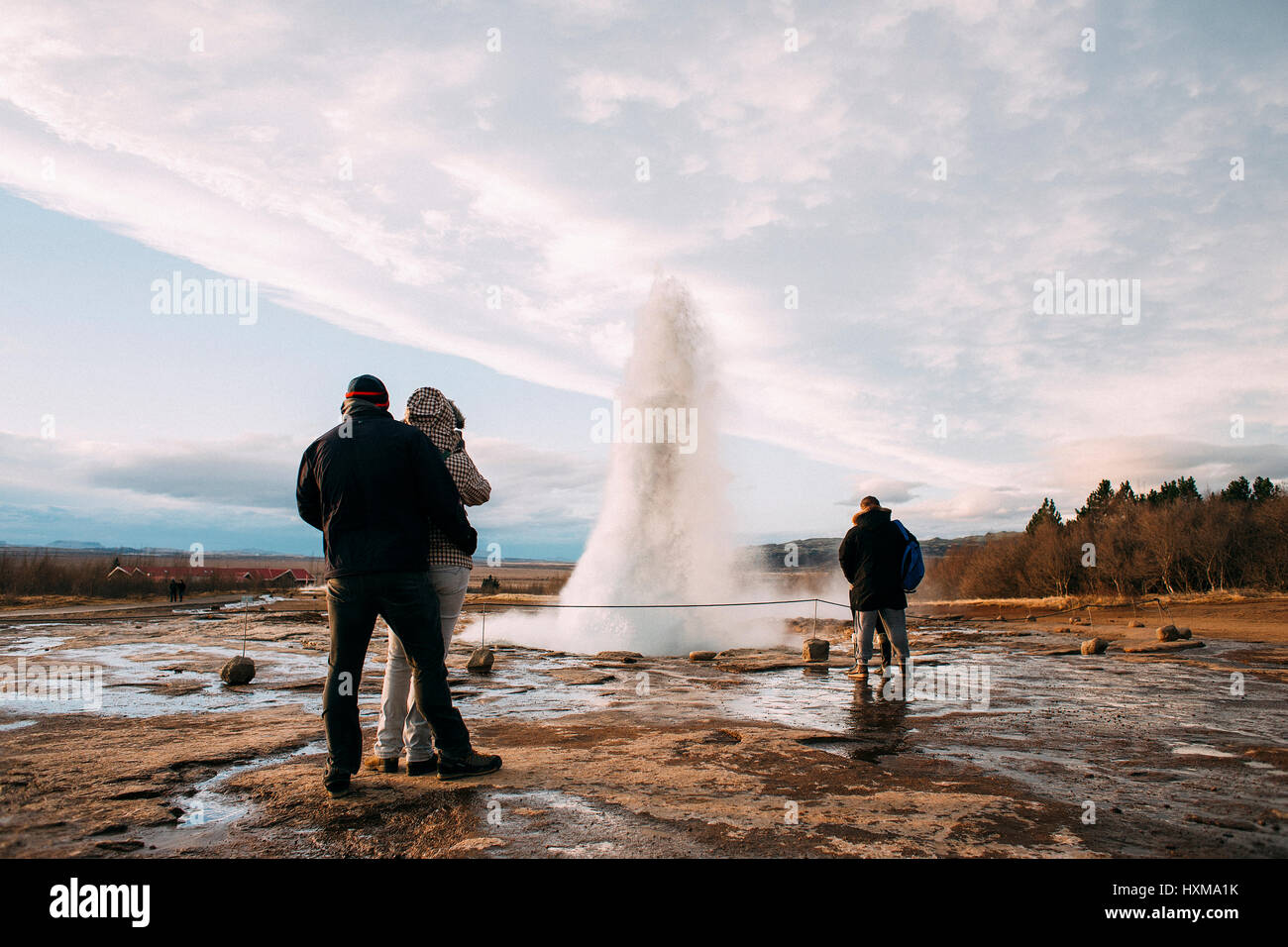 Touristen sind die Eruption des Strokkur-Geysirs in Island zu beobachten. Es ist Teil des Bereichs Haukadalur Geothermie und einer der bekanntesten Geysire Stockfoto