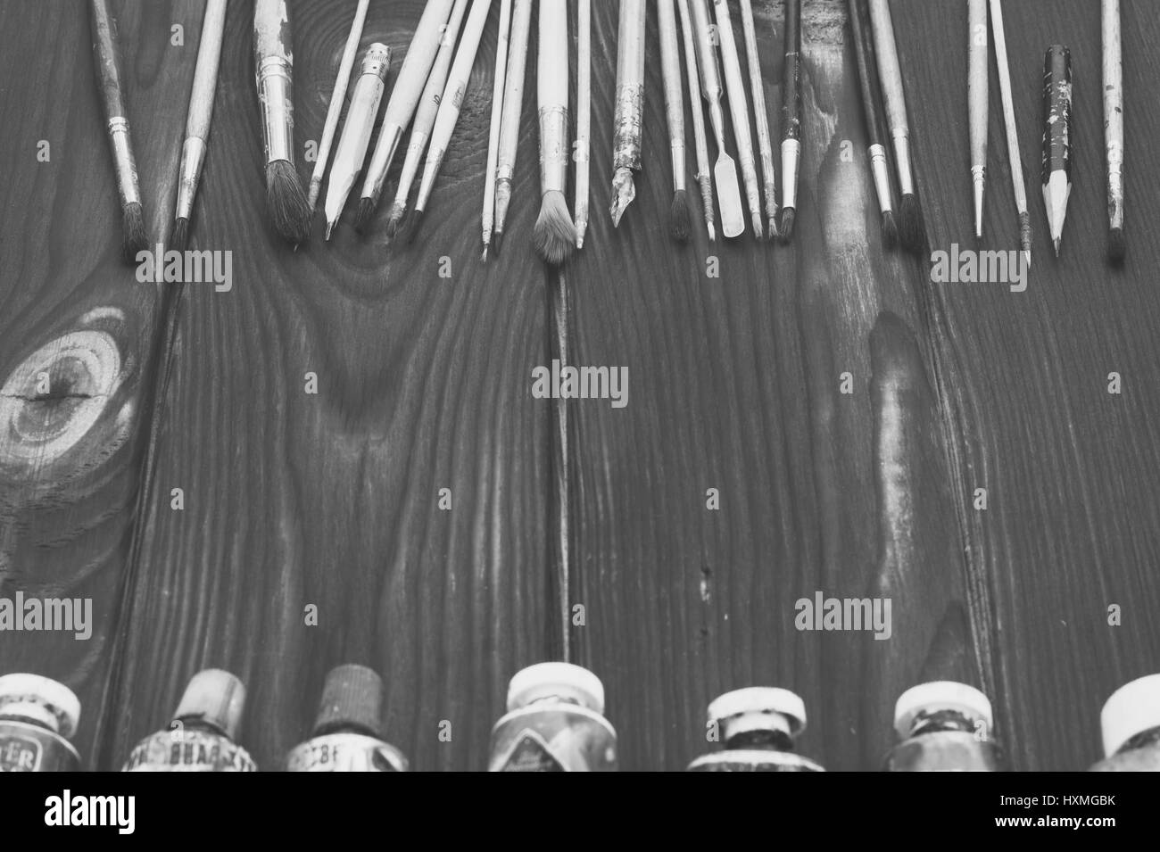 Pinsel und Farben sind auf dunklen Holzfläche verteilt Stockfoto