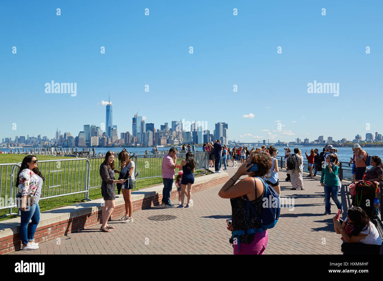 Touristen und Menschen in New York fotografieren und zu Fuß vor der Skyline der Stadt an einem sonnigen Tag Stockfoto