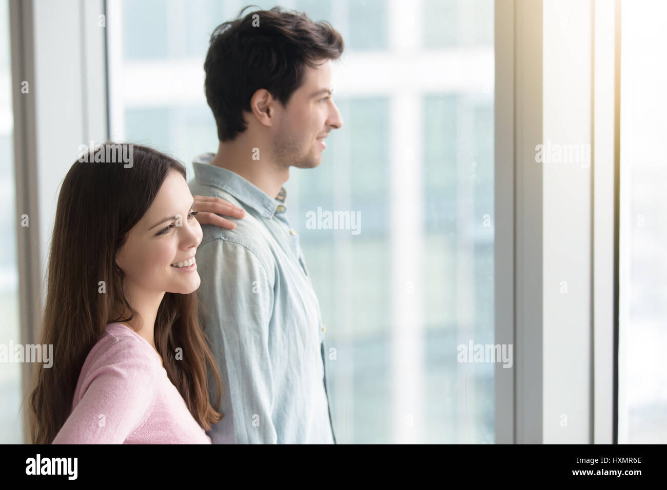 Mann und Frau, die durch Fenster auf Stadt-Landschaft, drinnen Stockfoto