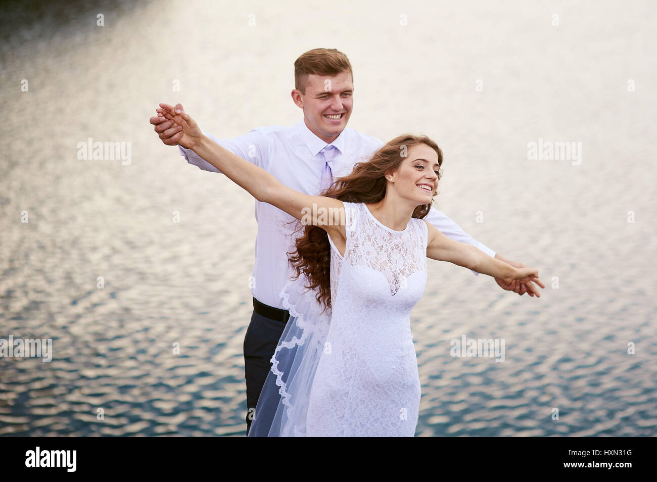 Glückliche Braut und Bräutigam auf eine Hochzeit gehen in der Nähe der See-Umarmung Stockfoto