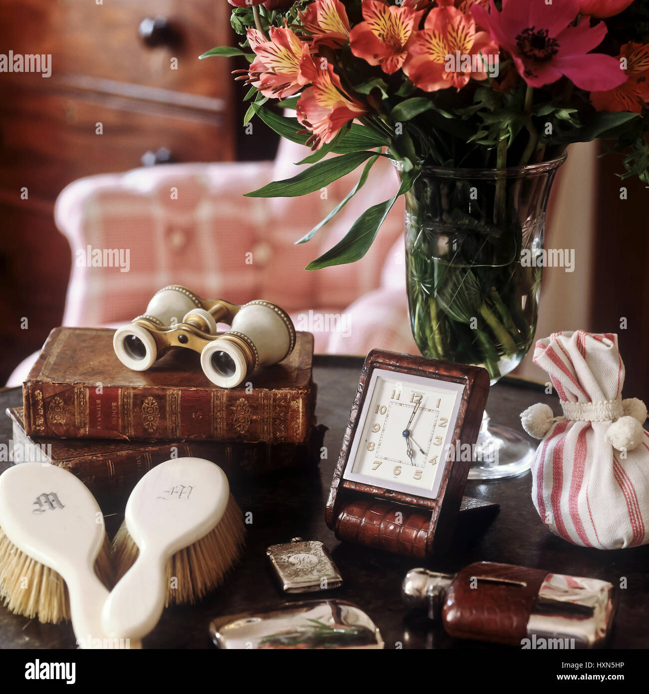 Vase mit Blumen und Antiquitäten auf Tisch. Stockfoto