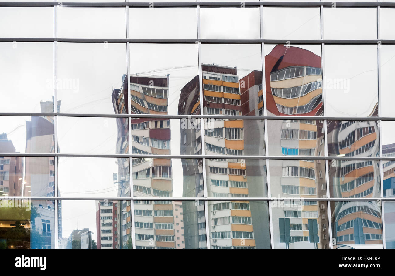Verzerrten Reflexion von Wohngebäuden in Spiegeloberfläche der Verkleidung des Einkaufszentrums ihnen gegenüber. Stockfoto