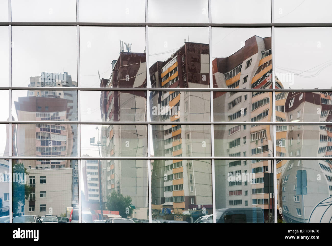 Verzerrtes Spiegelbild der mehrgeschossigen Wohnbau in Spiegeloberfläche der Verkleidung der Mall gegenüber beherbergt. Stockfoto