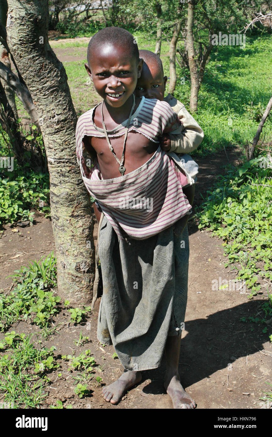 Meserani Snake Park, Arusha, Tansania - 14. Februar 2008: Ostafrika, eine unbekannte schwarze afrikanische Massai junge 10 Jahre alt, ist die jüngere Schwester hinter Stockfoto