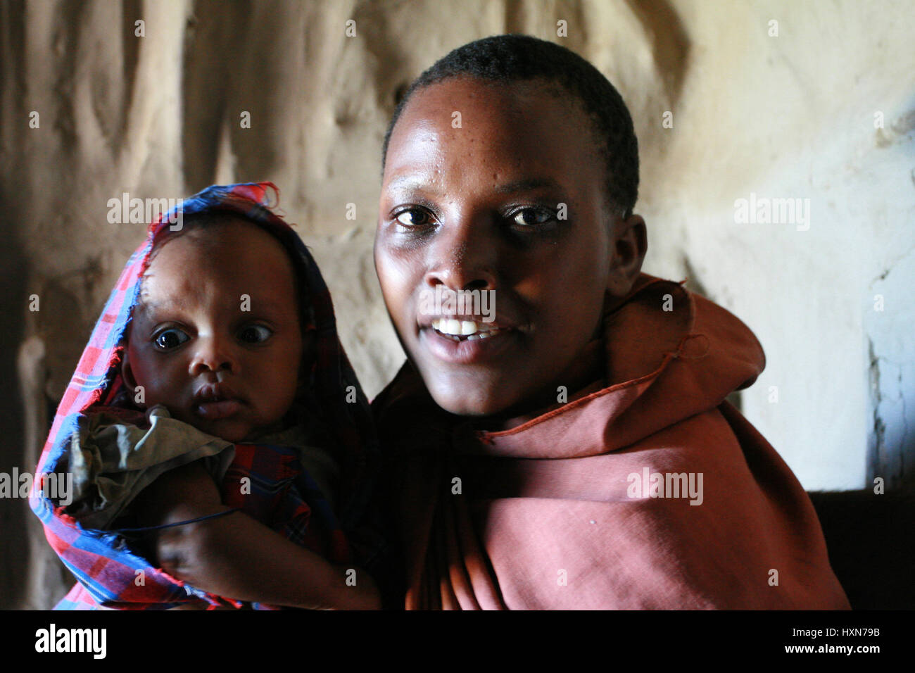 Meserani Snake Park, Arusha, Tansania - 14. Februar 2008: Das Innere der Heimat Maasai, schwarze Frau in drapierten Gewand, hält ein Baby, close-up herrsche Stockfoto