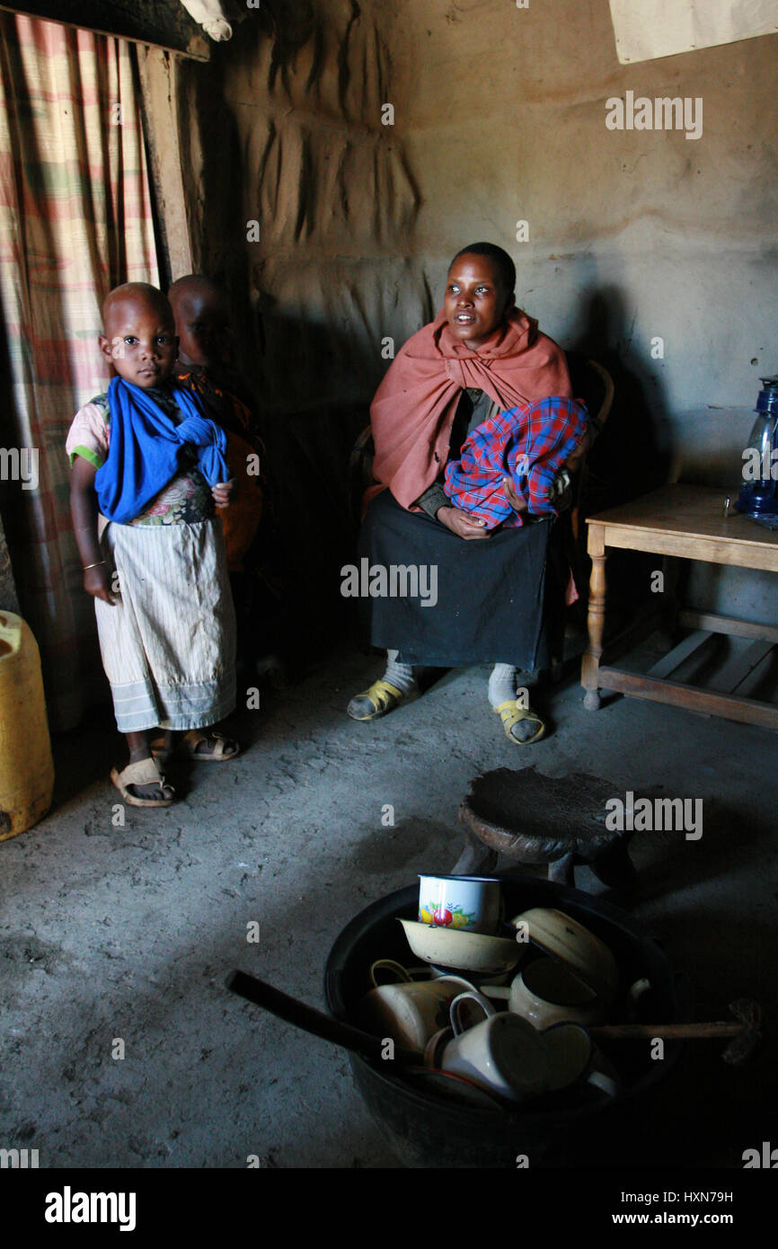 Meserani Snake Park, Arusha, Tansania - 14. Februar 2008: Das Innere der Heimat Maasai, Innenansicht der Hütte, eine schwarze Frau und Kinder Afric Stockfoto