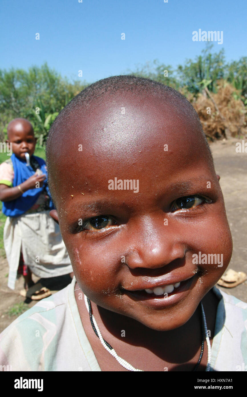 Meserani Snake Park, Arusha, Tansania - 14. Februar 2008: Unbekannte schwarze afrikanische Mädchen vom Stamm Massai, etwa 4 Jahre alt, mit kurzen Haaren und einem Stockfoto