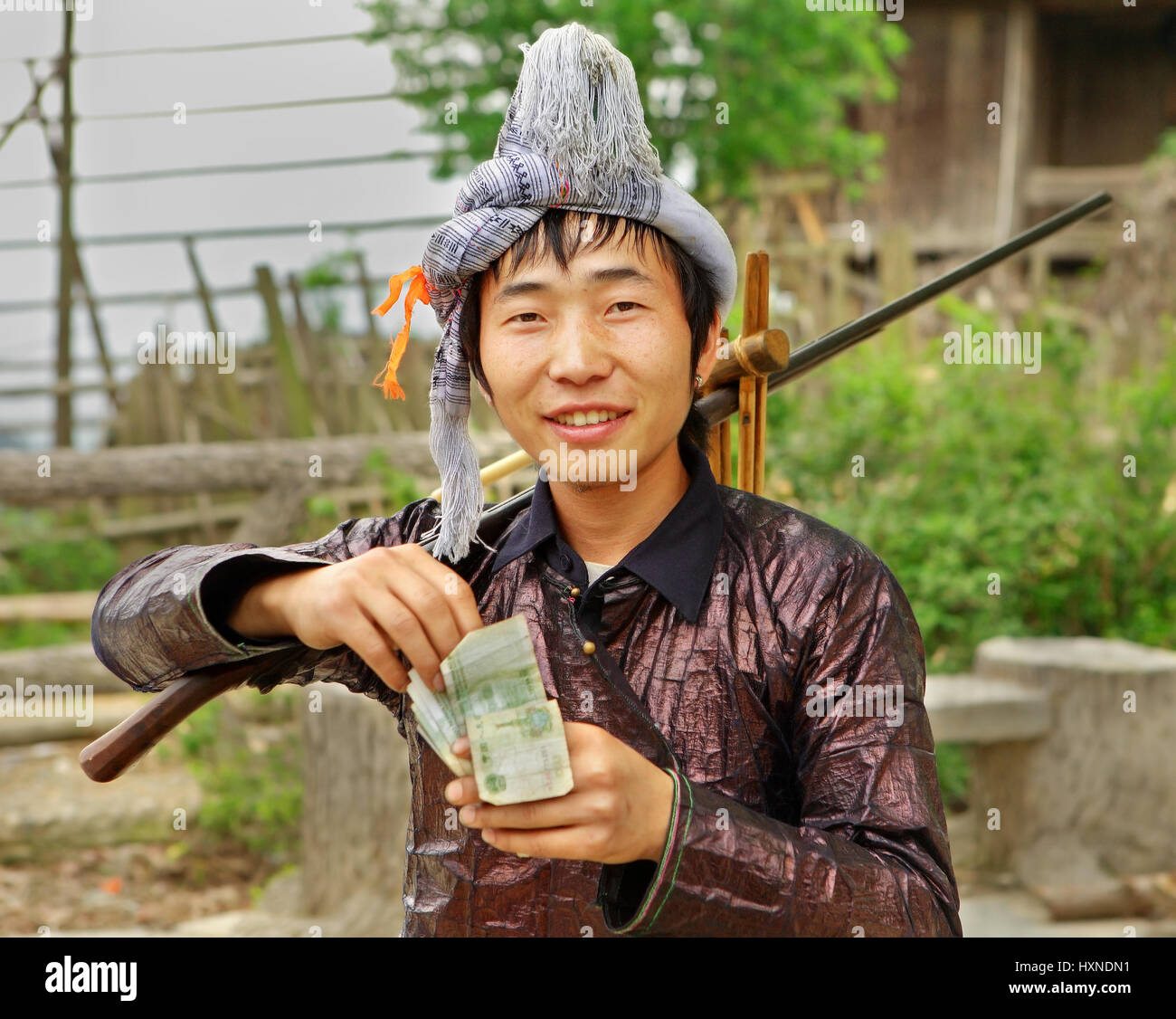 GUIZHOU PROVINZ; CHINA - APRIL 10: Mann Miao ethnische Gruppe, mit einer Muskete auf seiner Schulter verdient zählt Yuan im Dorf Festival 10. April 2010. BAS Stockfoto