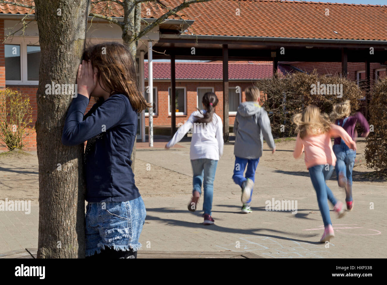 Kinder in der Grundschule spielen verstecken und suchen in Pause Stockfoto
