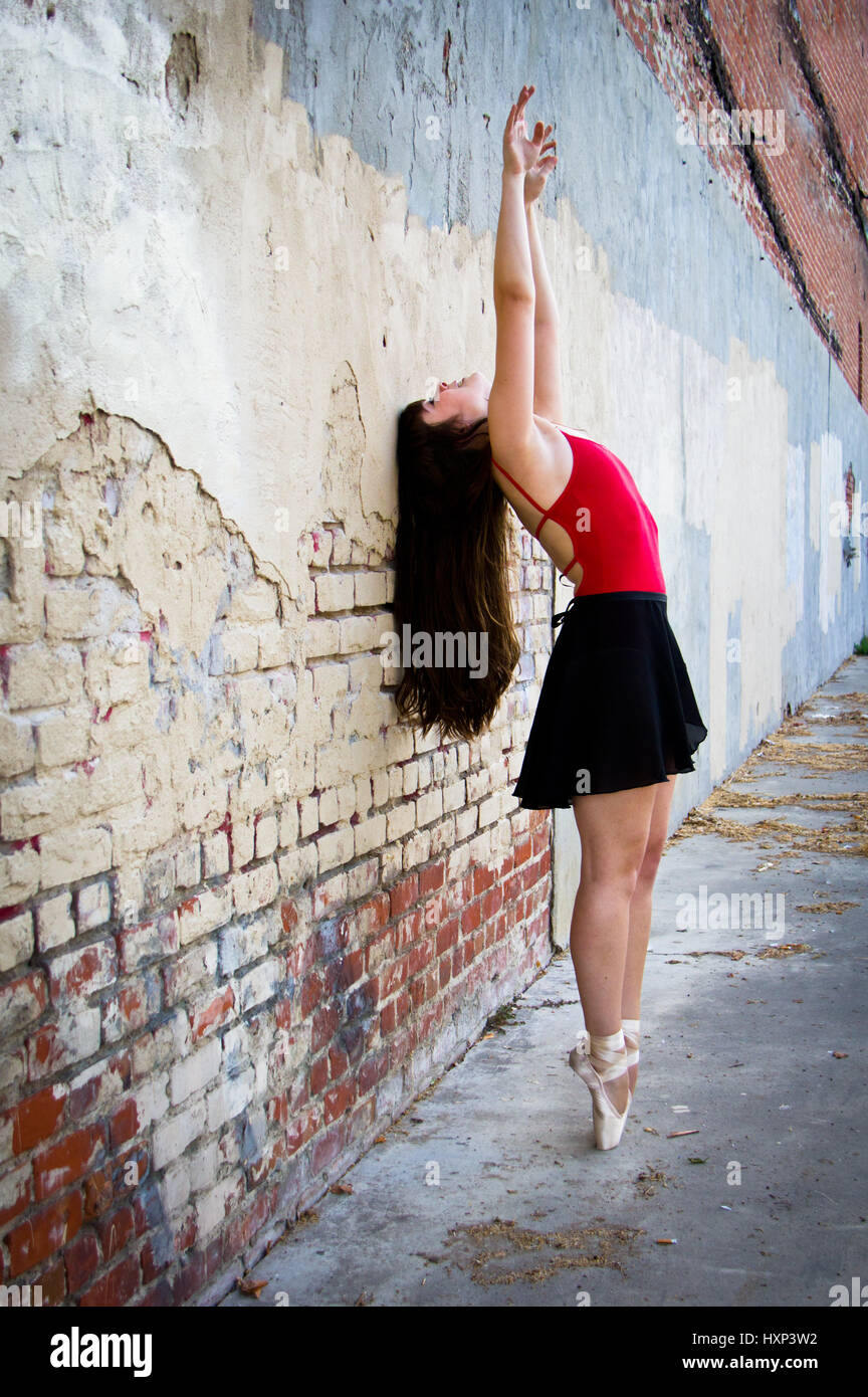 Jungen Ballerina bis auf Punkt mit Arme sich in Luft, wie sie nach oben in einer Gasse sucht Stockfoto