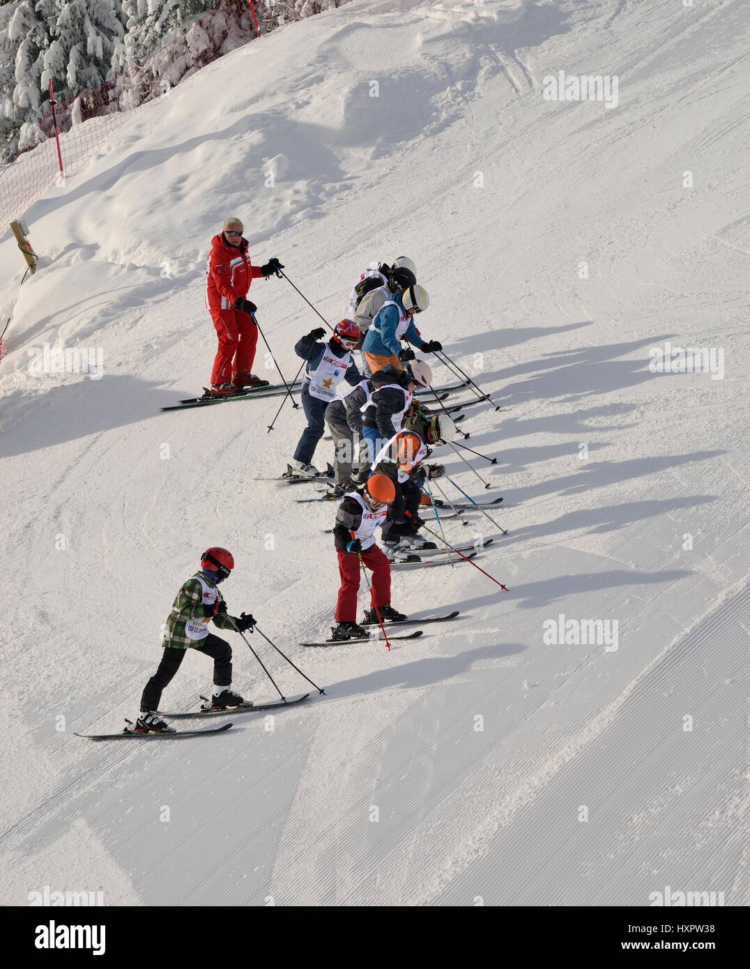 Skischule, aufgereiht auf einem steilen Piste, Les Contamines, Savoie, Frankreich, Februar. Stockfoto