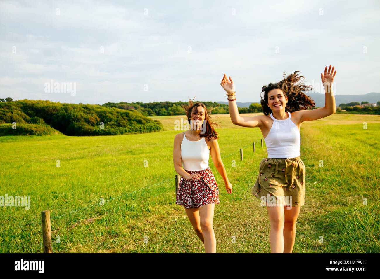 Lustige Freundinnen in einem grünen Feld springen Stockfoto