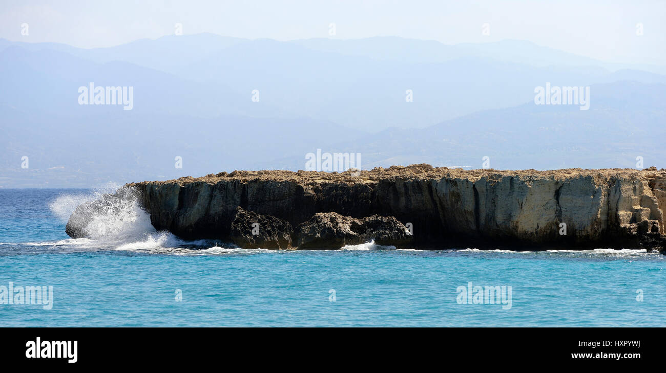 Sprühen Sie auf vulkanischem Gestein auf der kleinen Insel mit Gialia Wald Behnd Nordostküste der Halbinsel Akamas, Zypern Stockfoto