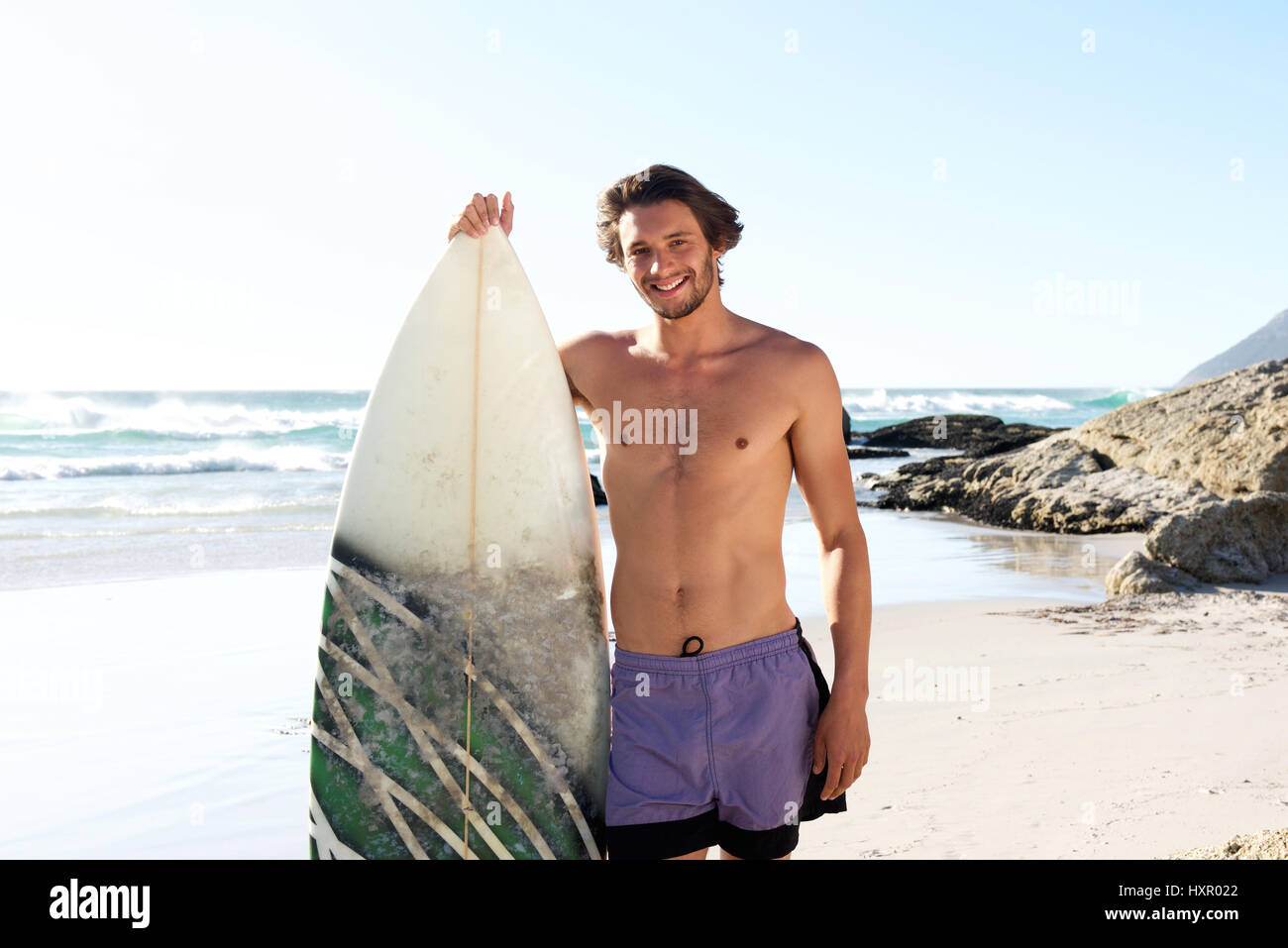 Porträt von einem Surf-Mann stehend mit Surfbrett am Strand Stockfoto