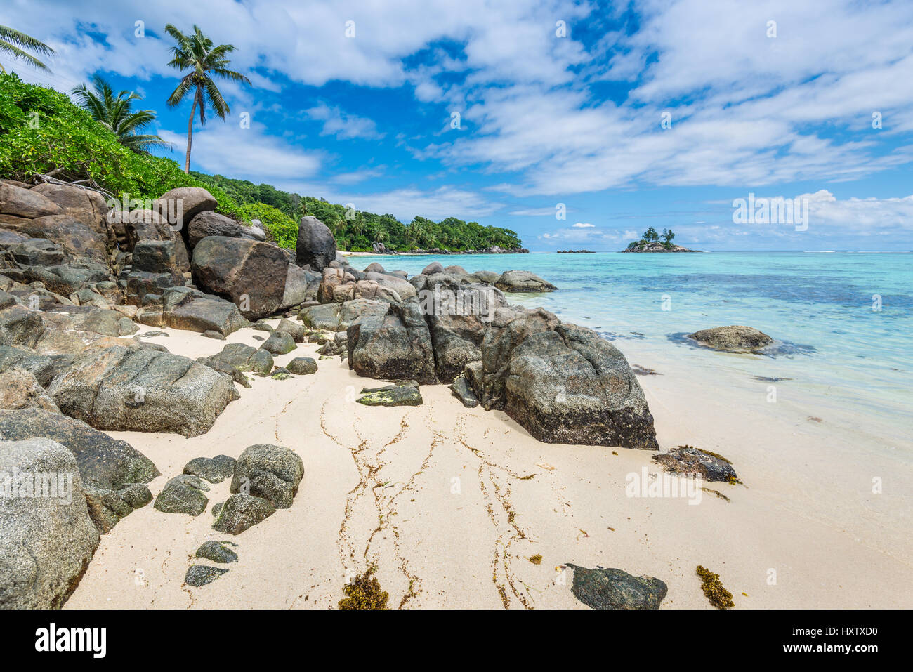 Tropischer Strand Anse Royale mit Granitfelsen im Vordergrund auf Mahé, Seychellen - Urlaub Hintergrund. Stockfoto