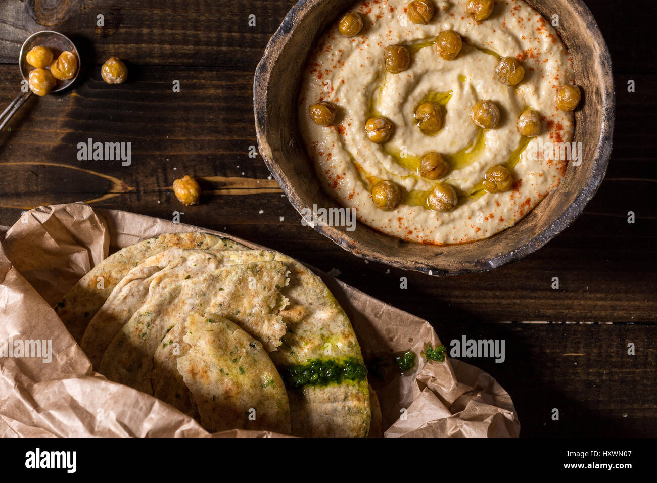 Hausgemachter Kichererbsen Hummus in rustikalen Schüssel mit Olivenöl und frischem Fladenbrot Stockfoto