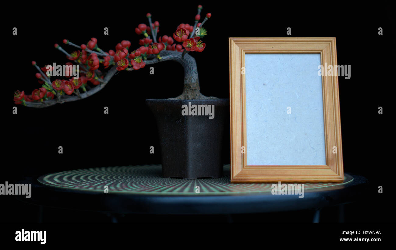 Leere Rahmen oder leere Bilderrahmen der vermissten Person mit Bonsai rote Blumen Stockfoto