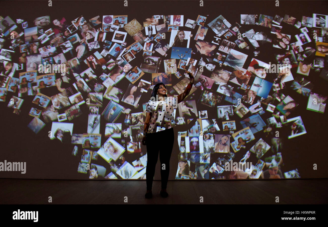 Ein Besucher schaut eine raumgreifende Installation von Selfie Fotos während einer Pressevorschau auf die Selfie Selbstdarstellung Ausstellung in der Saatchi Gallery in London, die die Geschichte der Selfie aus Portrait Künstler durch zum heutigen Selfies betrachtet. Stockfoto