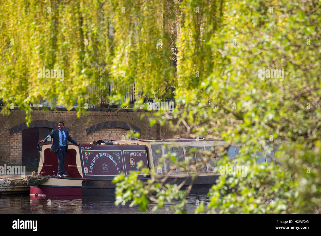 Ein Mann genießt die Sonne an Bord ein Narrowboat in Klein-Venedig, London, an einem Tag bei Temperaturen im Südosten von England erwartet wurden, um saisonale überdurchschnittlich hoch und erreichen 22 C. Stockfoto