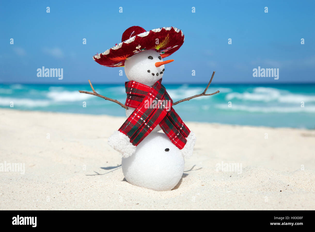 Miniatur-Schneemann trägt mexikanischen Sombrero und Schal am Strand von Cancun Stockfoto