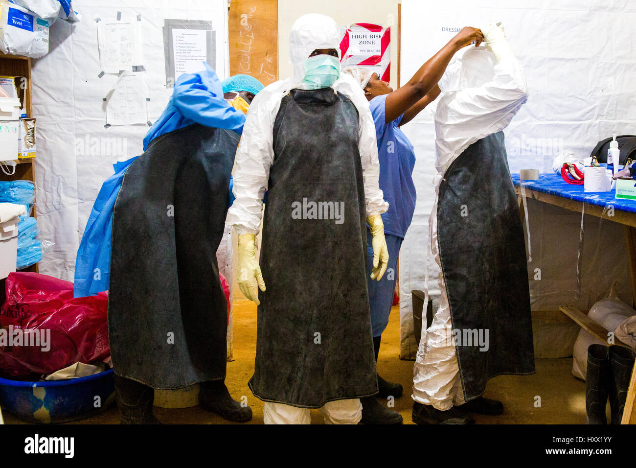 Mitarbeiter des Gesundheitswesens erhalten Kleider in Schutzkleidung (PSA) zur Vorbereitung ihrer Schicht mit ihren Patienten haben einige Ebola und andere. Stockfoto