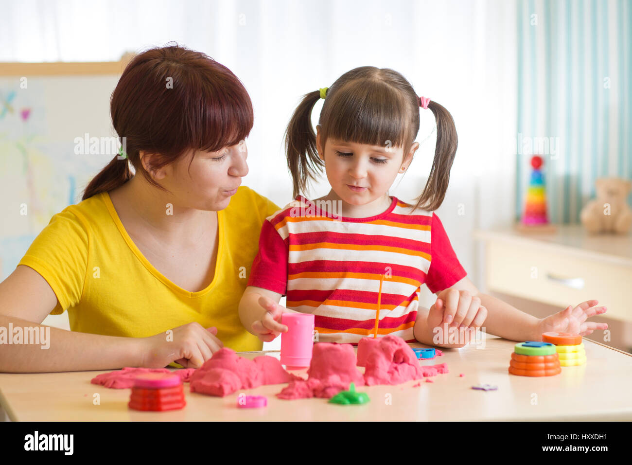 Kind Mädchen und Mutter spielen mit Spielzeug Sand zu Hause Stockfoto