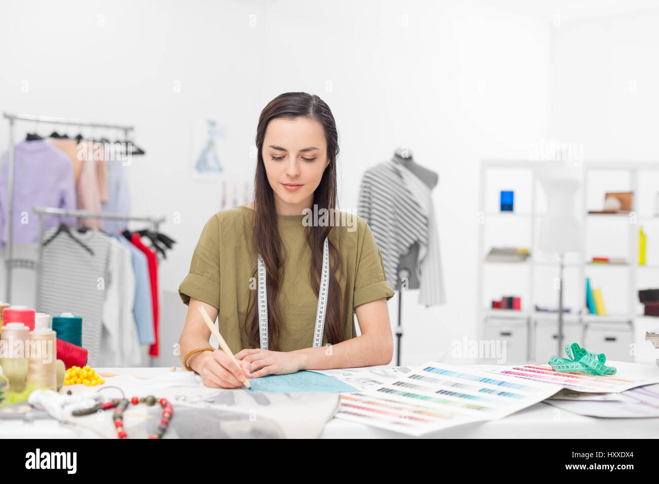 eine junge Modedesignerin, die Zeichnung auf dem Schreibtisch in ihrem showroom Stockfoto