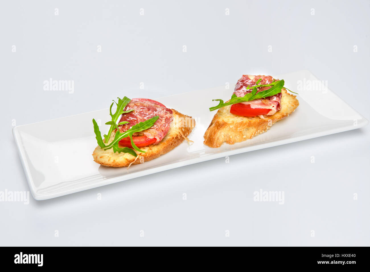 Zwei Bruschettes mit Serrano-Schinken, Käse und Rucola auf Platte Stockfoto