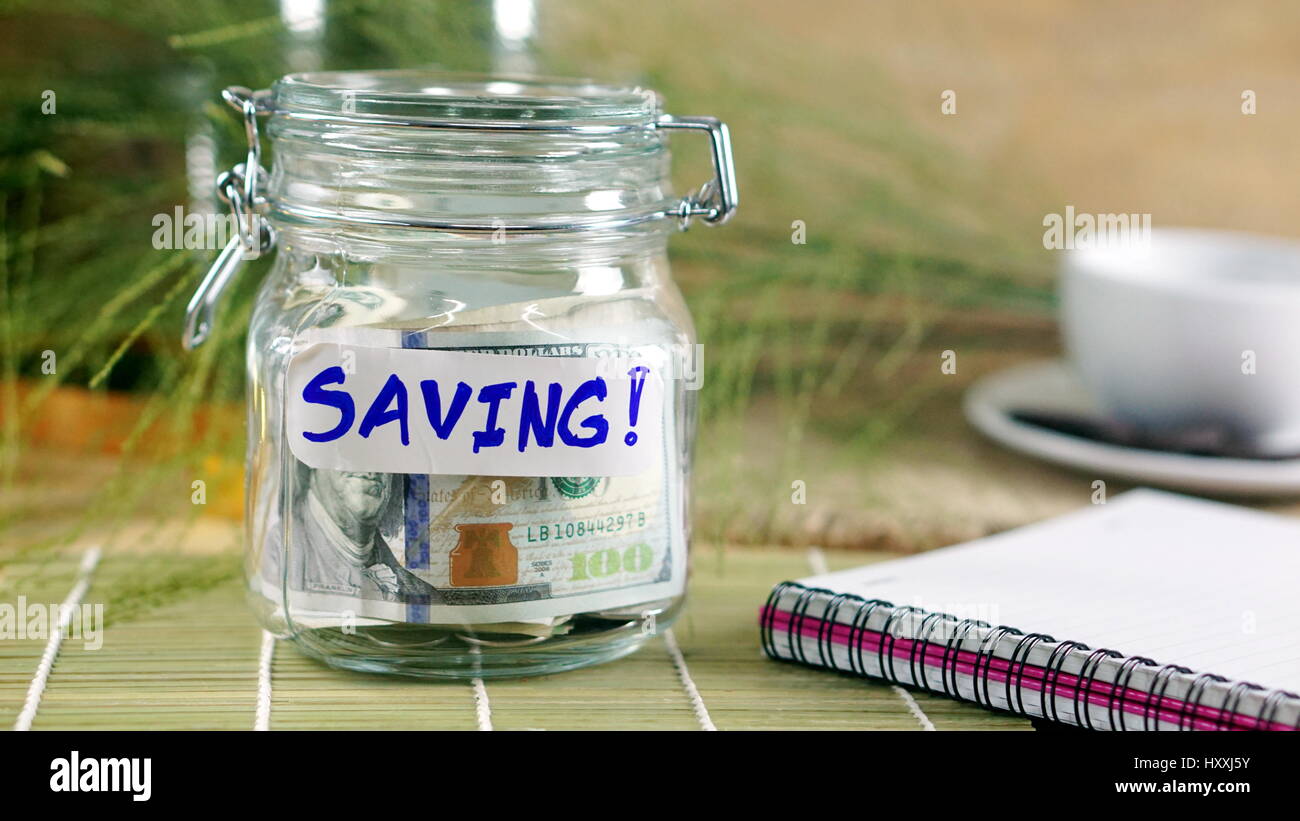 Geld sparen auf dem Holz Schreibtisch und Natur Hintergrund mit weißen notebook Stockfoto