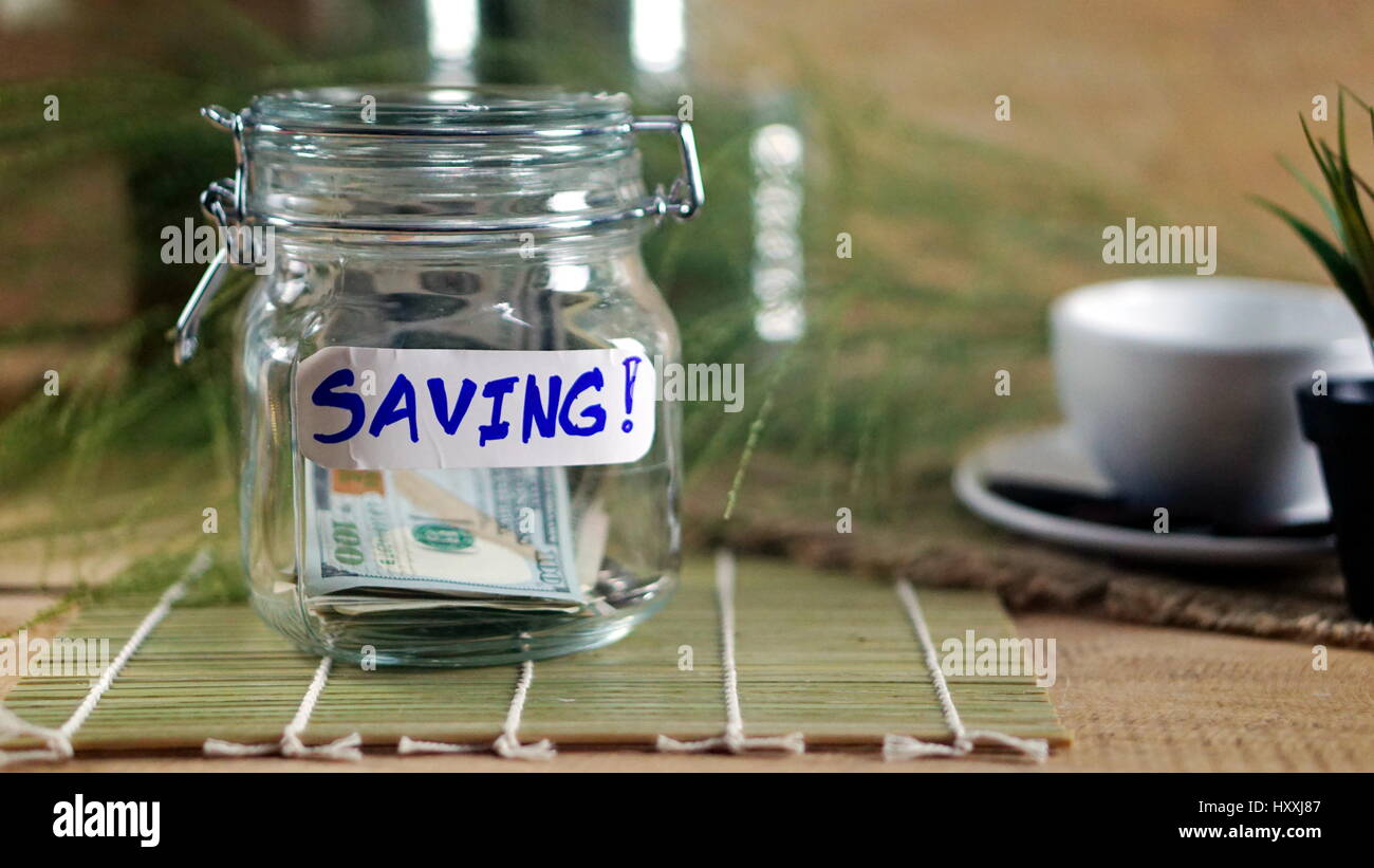 Geld sparen auf dem Holz Schreibtisch und Natur Hintergrund mit weißen notebook Stockfoto