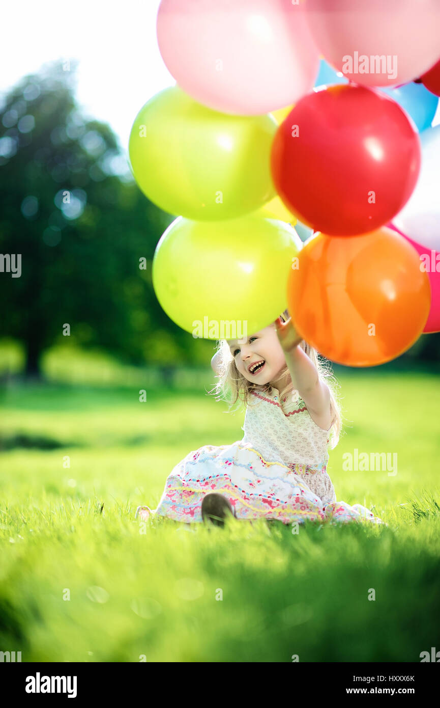 Blonde Mädchen spielen mit Haufen Luftballons auf dem Lande Stockfoto