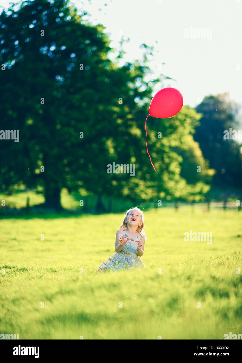 Blonde Mädchen loslassen von einem einzigen roten Ballon auf dem Lande Stockfoto