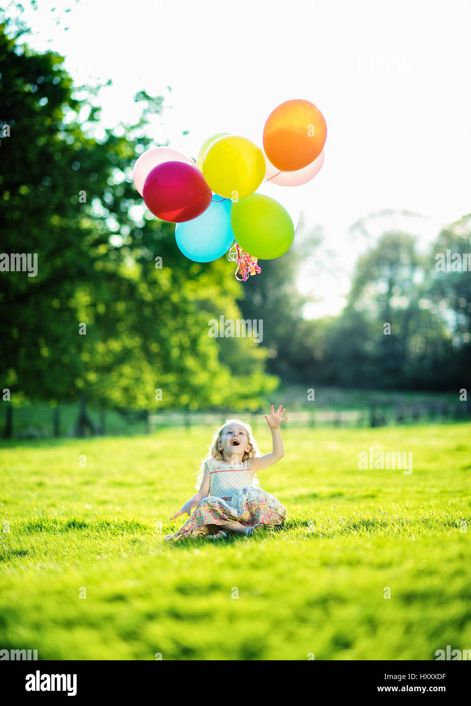 Blonde Mädchen spielen mit Haufen Luftballons auf dem Lande Stockfoto